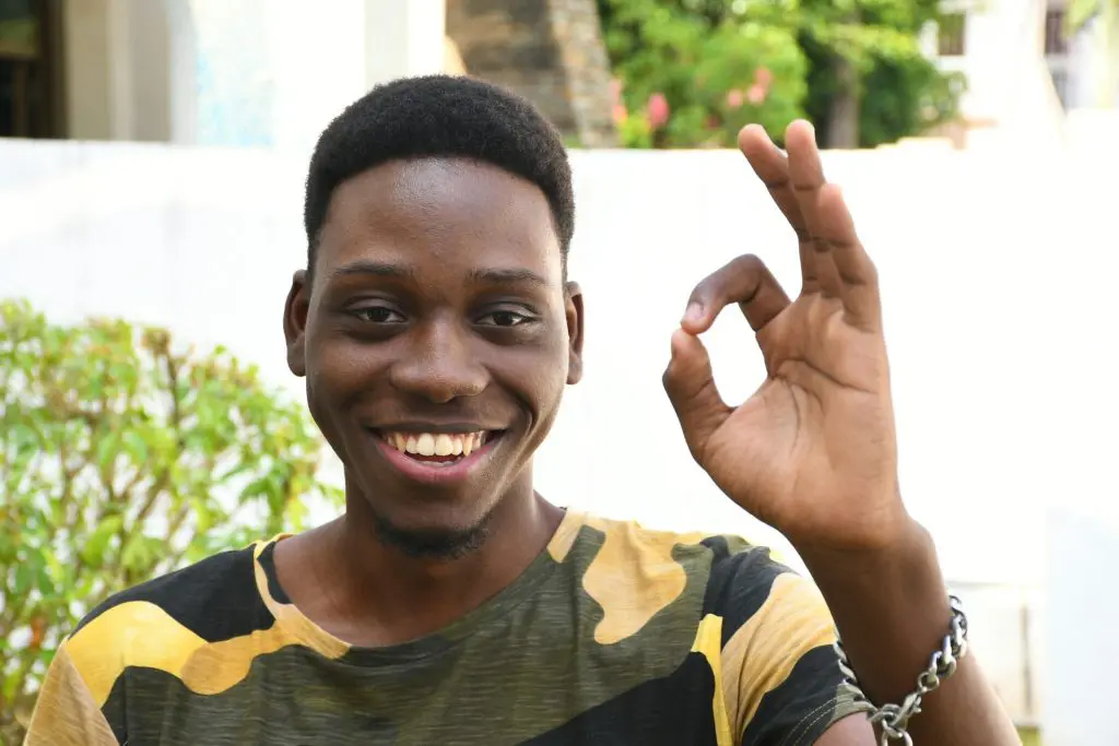 A man is smiling forming the "ok" symbol with his fingers.