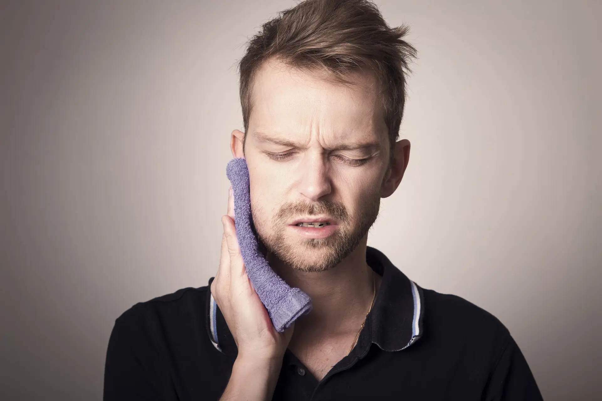 A man is holding a rag with ice pack to his jaw.
