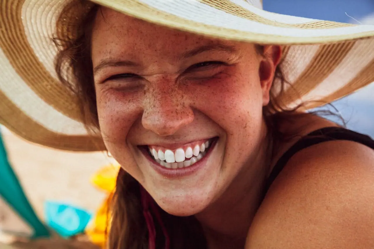 woman smiling wearing wide brim hat to lower risk of oral cancer