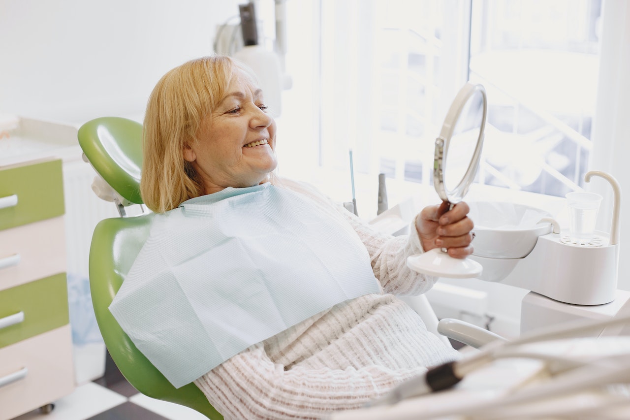 older woman in dentist chair smiling at mirror