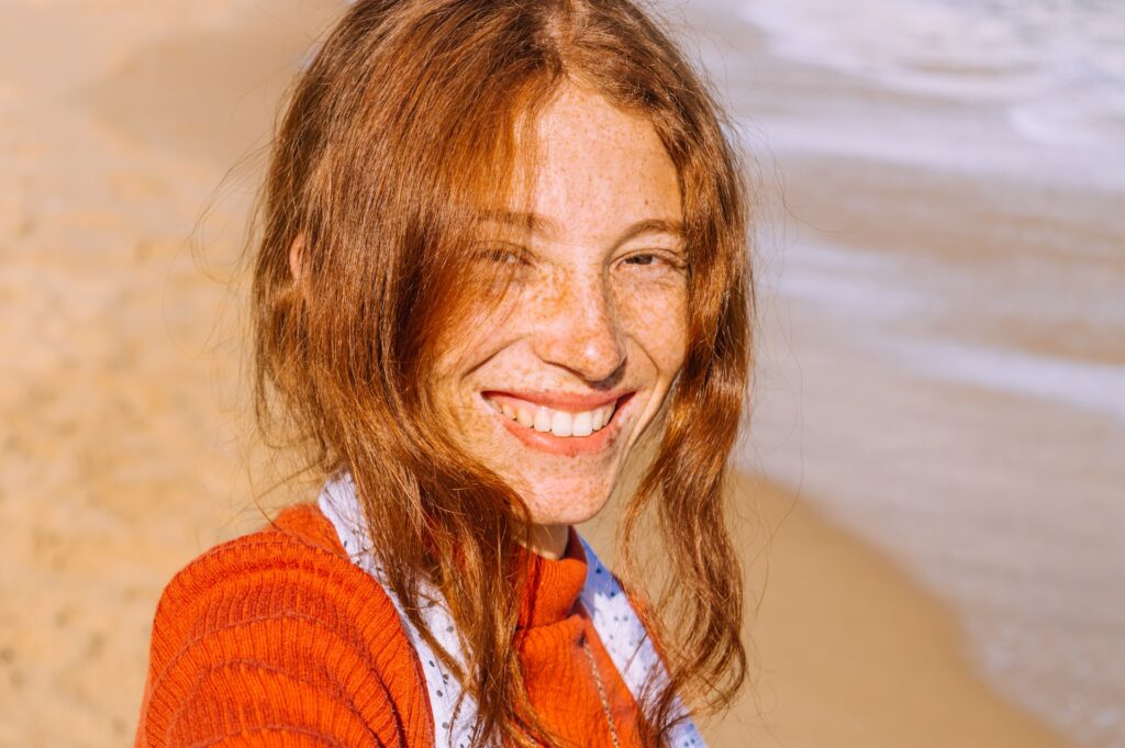 red haired woman smiling on beach
