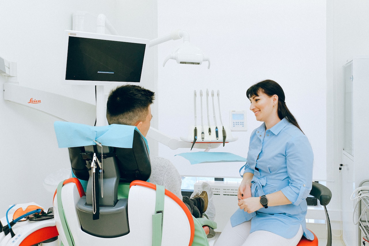man sitting in dental chair talking to dentist