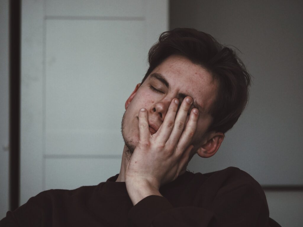 man in discomfort holding his hand to his face