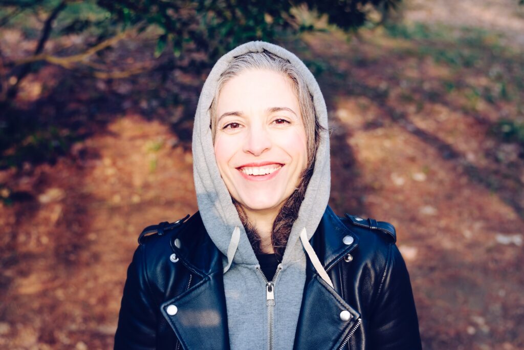 older woman in gray hoodie smiling outdoors