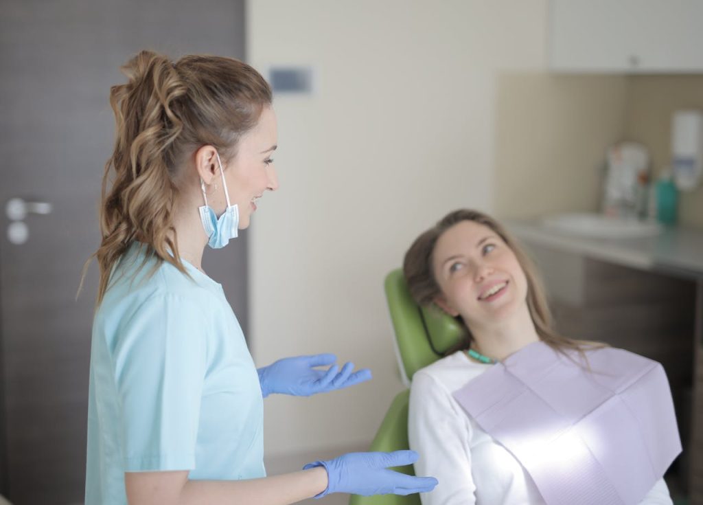 dentist and patient smiling and talking in exam room