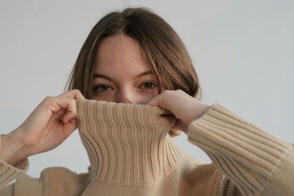 woman covering mouth with turtleneck sweater